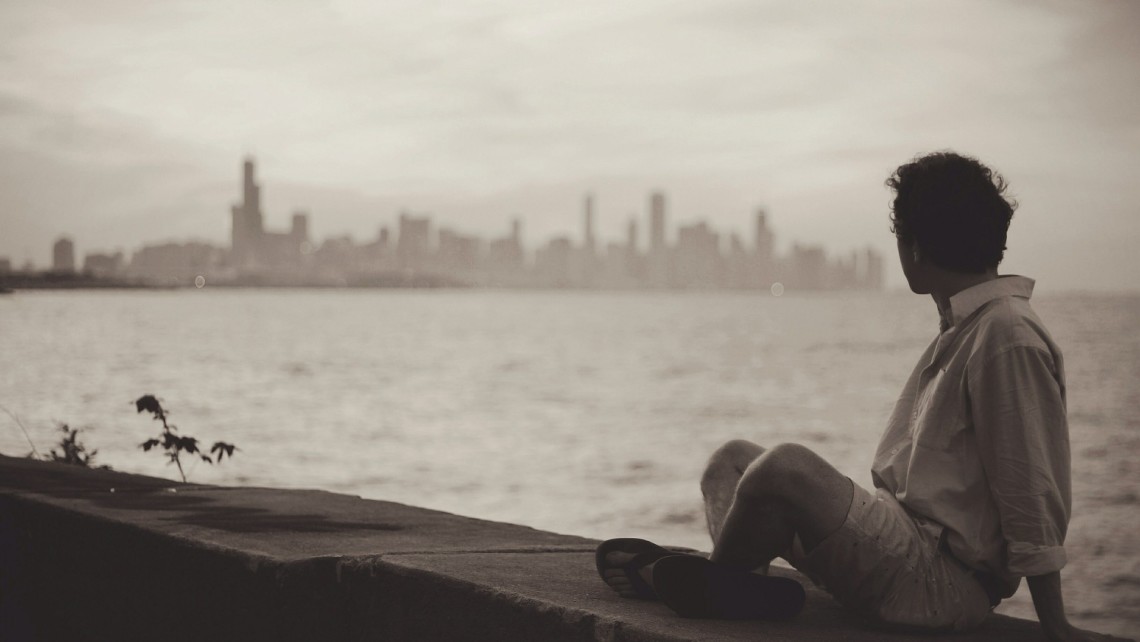 A man sitting, looking out toward the sea