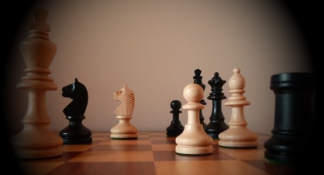 A chessboard with dark and light chess pieces on it.